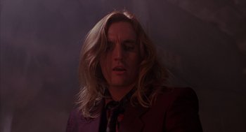 Movie still from “Darkman” (1990), directed by Sam Raimi – A man with long blonde hair wearing a purple suit; Close Up shot, Low angle