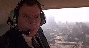 Movie still from “Darkman” (1990), directed by Sam Raimi – A man in a suit and tie wearing headphones; Close Up shot, Low angle