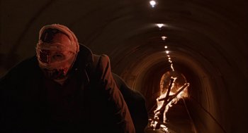 Movie still from “Darkman” (1990), directed by Sam Raimi – A person in a dark tunnel with lights on; Close Up shot, Low angle