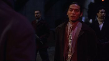 Movie still from “Darkman III: Die Darkman Die” (1996), directed by Bradford May – A man wearing a suit and tie standing next to another man; Medium shot, Over the shoulder angle