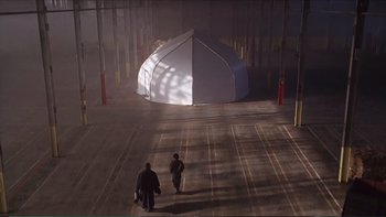 Movie still from “Darkman III: Die Darkman Die” (1996), directed by Bradford May – Two people walking in a parking lot near a tent; Extreme Wide shot, High angle