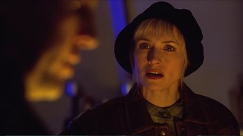 Movie still from “Darkman III: Die Darkman Die” (1996), directed by Bradford May – A woman wearing a black hat and a leather jacket; Close Up shot, Over the shoulder angle