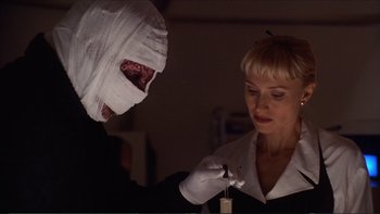 Movie still from “Darkman III: Die Darkman Die” (1996), directed by Bradford May – A woman holding a knife and a bandage on her head; Close Up shot, Low angle