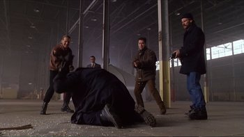 Movie still from “Darkman III: Die Darkman Die” (1996), directed by Bradford May – A group of men standing around a man laying on the ground; Wide shot, Low angle