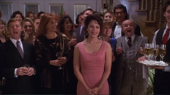 Movie still from “Darkman III: Die Darkman Die” (1996), directed by Bradford May – A woman in a pink dress standing in front of a group of people; Medium shot, High angle