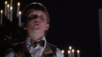 Movie still from “Darkman III: Die Darkman Die” (1996), directed by Bradford May – A young boy wearing a vest and bow tie; Close Up shot, Low angle