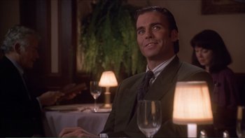 Movie still from “Darkman III: Die Darkman Die” (1996), directed by Bradford May – A man sitting at a table with a glass of wine in front of him; Close Up shot, Low angle