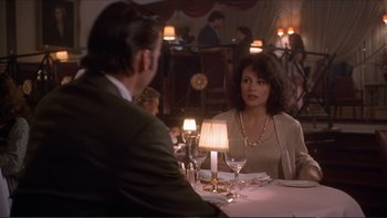 Movie still from “Darkman III: Die Darkman Die” (1996), directed by Bradford May – A man and a woman sitting at a table in front of candles; Medium shot, Over the shoulder angle