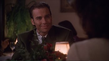 Movie still from “Darkman III: Die Darkman Die” (1996), directed by Bradford May – A person sitting at a dinner table; Close Up shot, Over the shoulder angle