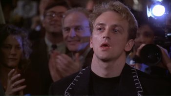 Movie still from “Darkman III: Die Darkman Die” (1996), directed by Bradford May – A man in a crowd of people is looking at the camera; Close Up shot, Low angle