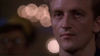 Movie still from “Darkman III: Die Darkman Die” (1996), directed by Bradford May – A man's face in front of blurry lights; Close Up shot, Low angle