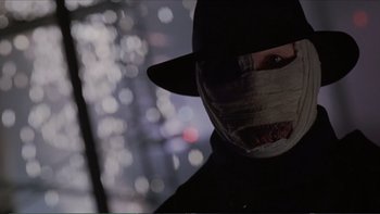 Movie still from “Darkman III: Die Darkman Die” (1996), directed by Bradford May – A person wearing a mask and a hat; Close Up shot, Low angle
