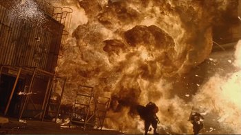 Movie still from “Darkman III: Die Darkman Die” (1996), directed by Bradford May – A man standing in front of an exploding structure; Wide shot, Low angle