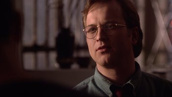 Movie still from “Darkman II: The Return of Durant” (1995), directed by Bradford May – A person wearing glasses and a tie; Close Up shot, Over the shoulder angle