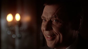 Movie still from “Darkman II: The Return of Durant” (1995), directed by Bradford May – A man's face in a dimly - lit room; Close Up shot, Over the shoulder angle