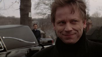 Movie still from “Darkman II: The Return of Durant” (1995), directed by Bradford May – A person with a car in the background; Close Up shot, Over the shoulder angle