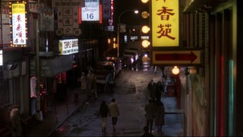 Movie still from “Darkman II: The Return of Durant” (1995), directed by Bradford May – People are walking down a street at night; Extreme Wide shot, High angle