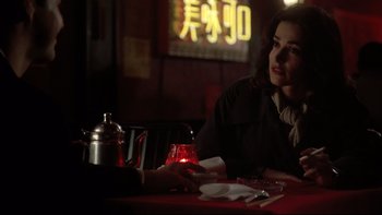 Movie still from “Darkman II: The Return of Durant” (1995), directed by Bradford May – A woman sitting at a table with a tea pot in front of her; Medium shot, Over the shoulder angle