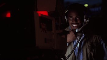 Movie still from “Darkman II: The Return of Durant” (1995), directed by Bradford May – A man with headphones is smiling for the camera; Close Up shot, Low angle