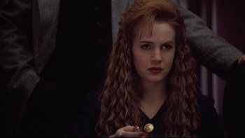 Movie still from “Darkman II: The Return of Durant” (1995), directed by Bradford May – A woman with long red hair holding a button; Close Up shot, Over the shoulder angle