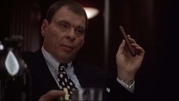 Movie still from “Darkman II: The Return of Durant” (1995), directed by Bradford May – A person holding a cigar and a glass; Close Up shot, Low angle