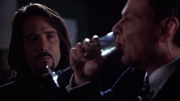 Movie still from “Darkman II: The Return of Durant” (1995), directed by Bradford May – A man drinking a glass of wine next to another man; Close Up shot, Over the shoulder angle