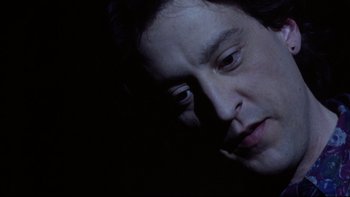 Movie still from “Darkman II: The Return of Durant” (1995), directed by Bradford May – A man is looking down at his face in the dark; Close Up shot, Low angle