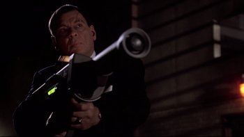 Movie still from “Darkman II: The Return of Durant” (1995), directed by Bradford May – A man in a suit holding a gun in the dark; Close Up shot, Low angle
