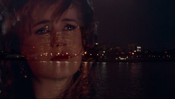 Movie still from “Darkman II: The Return of Durant” (1995), directed by Bradford May – A woman with her eyes closed in front of a city skyline at night; Close Up shot, High angle