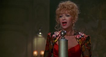 Movie still from “Das Boot” (1981), directed by Wolfgang Petersen – A woman in a red and gold dress singing into a microphone; Close Up shot, Low angle