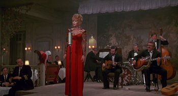 Movie still from “Das Boot” (1981), directed by Wolfgang Petersen – A woman in a red dress singing in front of a crowd; Wide shot, Low angle