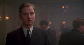Movie still from “Das Boot” (1981), directed by Wolfgang Petersen – A man wearing a suit and tie in a room; Close Up shot, Over the shoulder angle