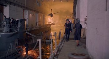 Movie still from “Das Boot” (1981), directed by Wolfgang Petersen – Two people walking down a street next to an old boat; Extreme Wide shot, High angle