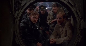 Movie still from “Das Boot” (1981), directed by Wolfgang Petersen – A group of men sitting in a ship's porthole; Medium shot, High angle