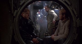 Movie still from “Das Boot” (1981), directed by Wolfgang Petersen – A group of people sitting in a room; Medium shot, Over the shoulder angle