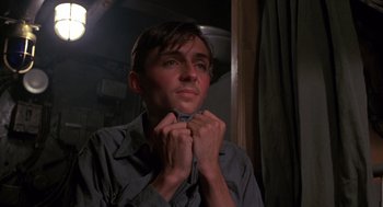 Movie still from “Das Boot” (1981), directed by Wolfgang Petersen – A young man is adjusting his tie in a dimly - lit room; Close Up shot, Low angle
