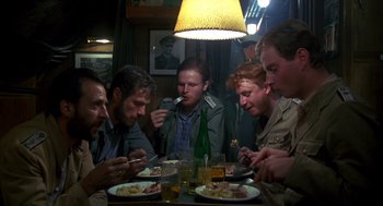 Movie still from “Das Boot” (1981), directed by Wolfgang Petersen – A group of people sitting at a table with plates of food; Medium shot, High angle