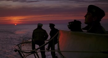 Movie still from “Das Boot” (1981), directed by Wolfgang Petersen – Two men standing on the deck of a boat at sunset; Wide shot, Low angle