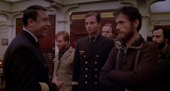 Movie still from “Das Boot” (1981), directed by Wolfgang Petersen – A group of men standing next to each other in a room; Medium shot, Over the shoulder angle