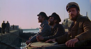 Movie still from “Das Boot” (1981), directed by Wolfgang Petersen – A group of men sitting next to each other on top of a boat; Medium shot, Low angle
