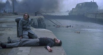 Movie still from “Das Boot” (1981), directed by Wolfgang Petersen – Two men laying on the ground next to a body of water; Wide shot, High angle