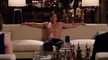 Movie still from “Date Night” (2010), directed by Shawn Levy – A man sitting on top of a white couch in a living room; Medium shot, Over the shoulder angle