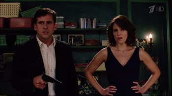 Movie still from “Date Night” (2010), directed by Shawn Levy – A man and a woman standing next to each other holding a gun; Medium shot, Over the shoulder angle
