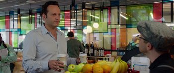 Movie still from “The Internship” (2013), directed by Shawn Levy – A man holding a cup of coffee in front of a table of fruit; Medium shot, Over the shoulder angle