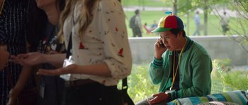 Movie still from “The Internship” (2013), directed by Shawn Levy – A young boy wearing a hat is talking on a cell phone; Medium shot, Over the shoulder angle