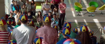 Movie still from “The Internship” (2013), directed by Shawn Levy – A group of people sitting in front of each other wearing clown hats; Wide shot, Over the shoulder angle