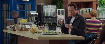 Movie still from “The Internship” (2013), directed by Shawn Levy – A man sitting at a table in front of a television; Medium shot, Over the shoulder angle
