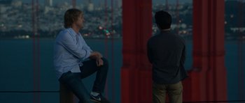 Two men are sitting on a pillar overlooking the city