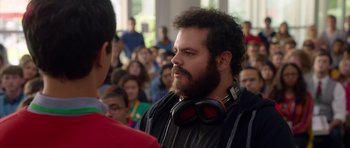 Movie still from “The Internship” (2013), directed by Shawn Levy – A man with a beard wearing headphones in front of a group of people; Close Up shot, Over the shoulder angle