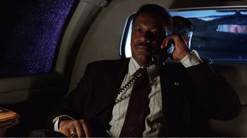 Movie still from “Dave” (1993), directed by Ivan Reitman – A man in a suit talking on a phone; Medium shot, Low angle